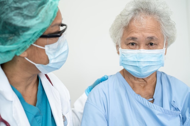 El médico ayuda a una paciente asiática mayor o anciana que usa una máscara facial en el hospital para proteger la infección de seguridad y matar el coronavirus Covid19