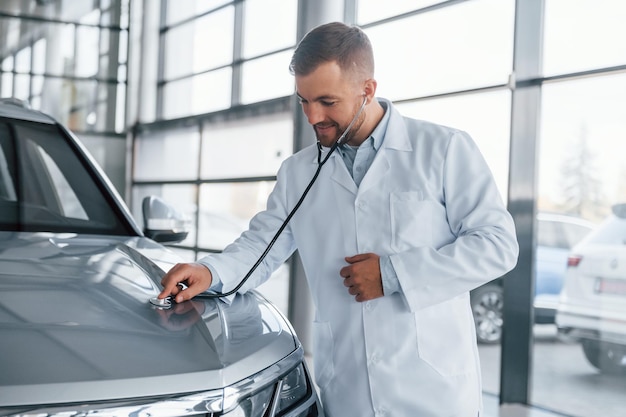 Médico de bata blanca está usando estetoscopio en el automóvil