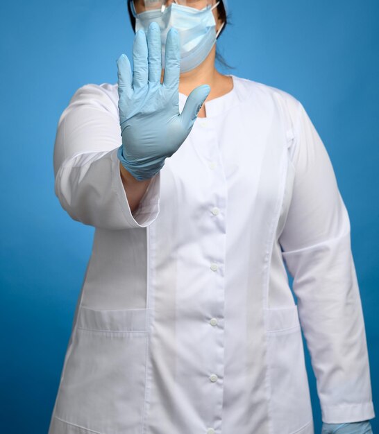 Foto el médico con bata médica blanca y guantes de látex azul muestra el concepto de gesto de detención de mantener un seguro