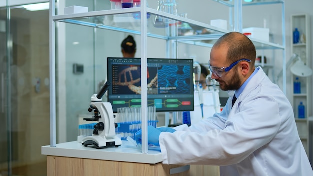 Médico biólogo verificando amostras de dna em um moderno laboratório equipado. equipe multiétnica examinando a evolução da vacina em laboratório médico usando ferramentas de alta tecnologia e química para pesquisa científica.