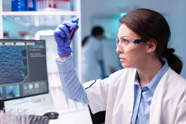 Foto médico biotecnologista analisando tubo de sangue para investigação médica