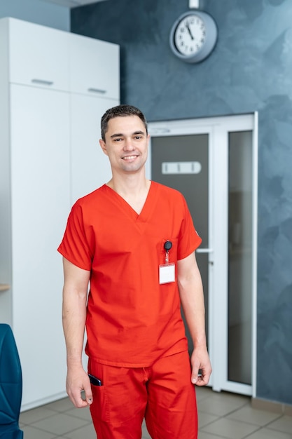 Médico bonito profissional em uniforme vermelho permanente no hospital. Médico de saúde na nova clínica moderna.