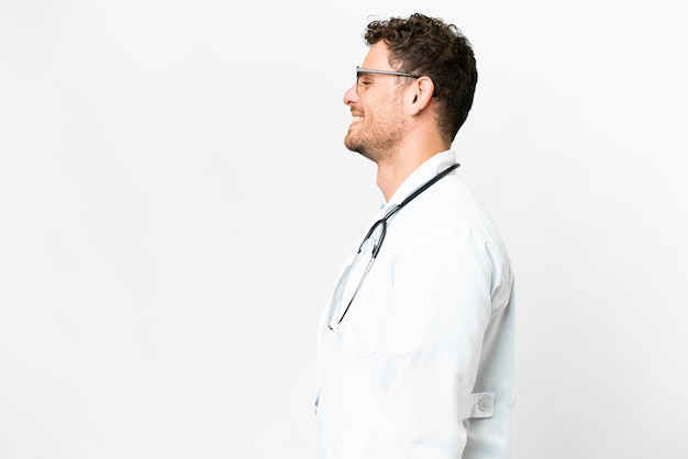 Médico brasileiro sobre fundo branco isolado rindo em posição lateral