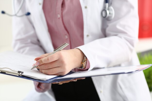 Médico brazo sosteniendo la pluma de plata llenado del paciente