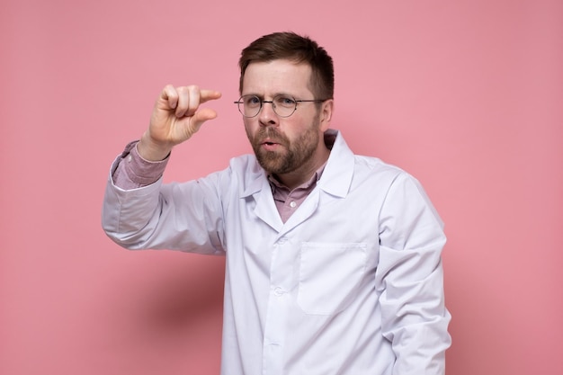 El médico burlón con gafas redondas muestra un tamaño pequeño con los dedos