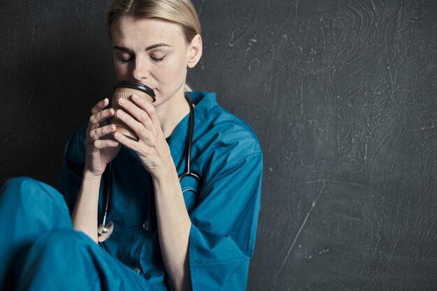 Médico cansado segurando uma xícara de café depois de receber um grande número de pacientes devido à epidemia de coronavírus