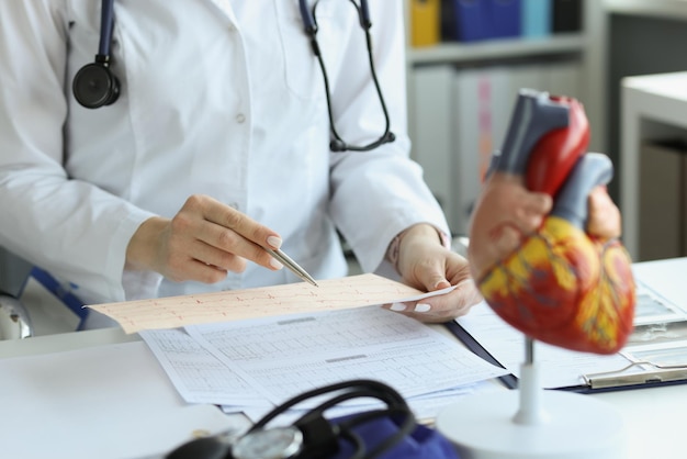 Médico cardiólogo sosteniendo y leyendo un informe de papel de ecg de un paciente con enfermedad cardíaca