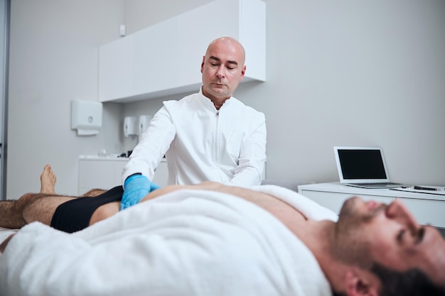 Médico careca examinando estômago masculino no escritório