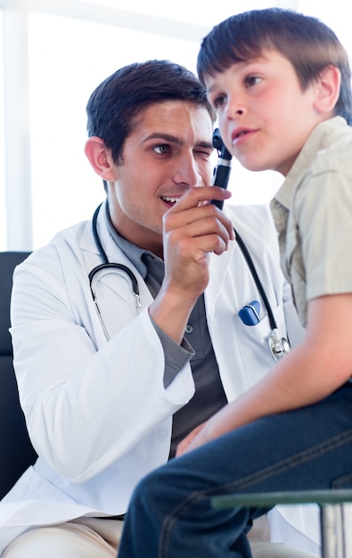 Médico carismático examinando as orelhas do menino