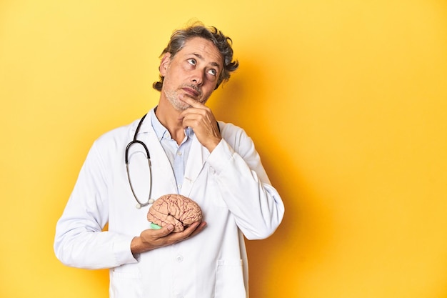 Médico caucásico de mediana edad sosteniendo un modelo de cerebro en el estudio