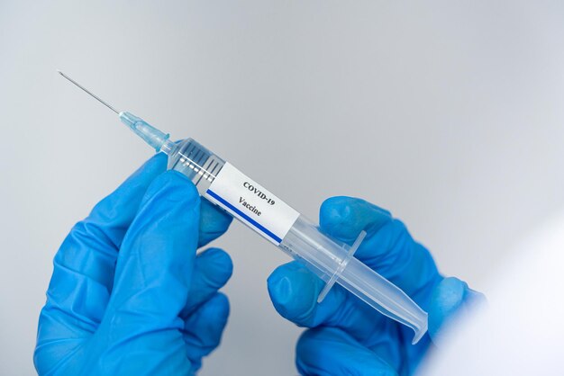 Médico científico investigador con guantes azules o traje de protección preparándose para ensayos clínicos de inyección humana vacunación contra el coronavirus covid-19 vacunación concepto de peligro biológico