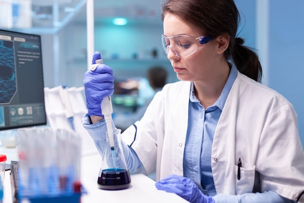 Médico cientista de jaleco branco descobrindo infecção genética e analisando micropipeta