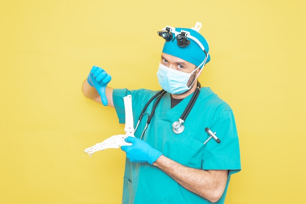 Médico cirujano joven vestido de verde sobre fondo amarillo