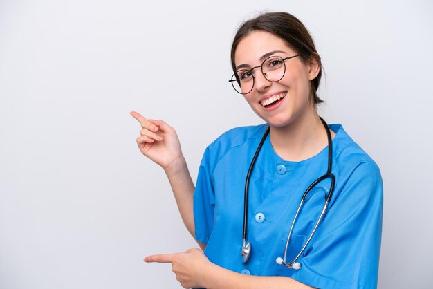 Médico cirujano mujer sosteniendo herramientas aisladas sobre fondo blanco sorprendido y apuntando hacia el lado