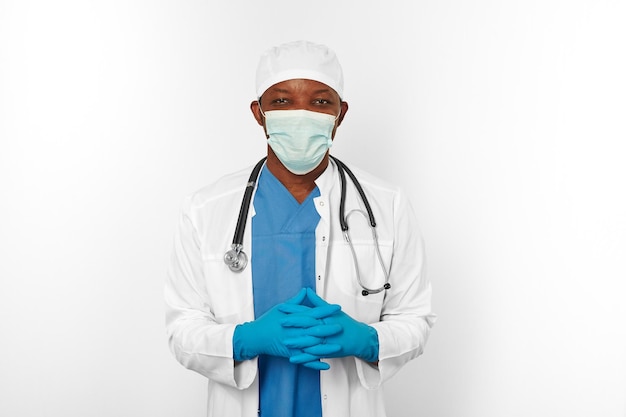 Médico cirujano negro hombre con bata blanca azul guantes azules gorra blanca y máscara de cirujano con estetoscopio