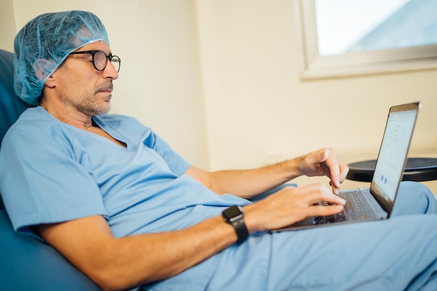 Médico cirujano usando laptop después de la operación