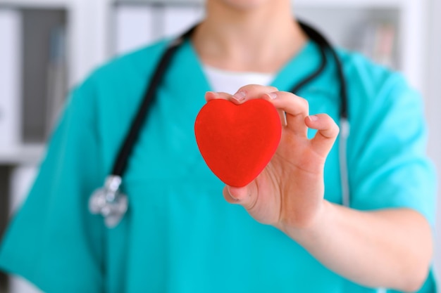 Médico cirurgião feminino com estetoscópio segurando o coração.