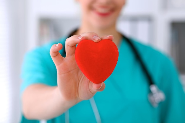 Médico cirurgião feminino com estetoscópio segurando o coração.