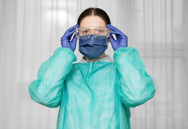 Foto médico coloca óculos de segurança, proteção contra coronavírus, medidas de segurança, preparação para o trabalho de um médico