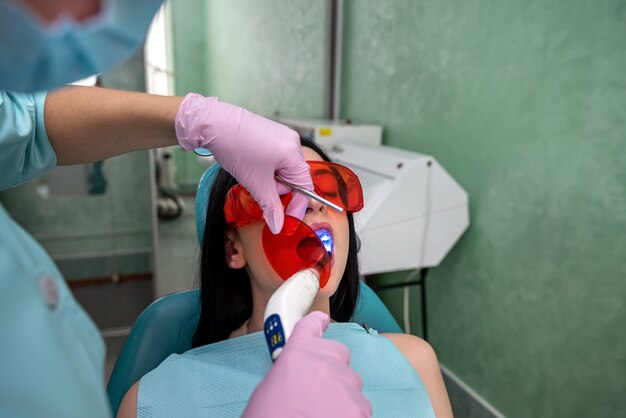 Médico com lâmpada e espelho tratando os dentes dos pacientes de perto