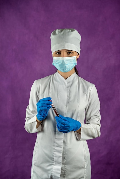 Médico com máscara médica e luvas azuis segurando tubo de ensaio com amostra de sangue para teste de coronavírus