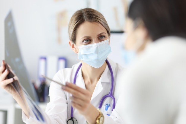 Médico com máscara protetora mostrando radiografia do paciente