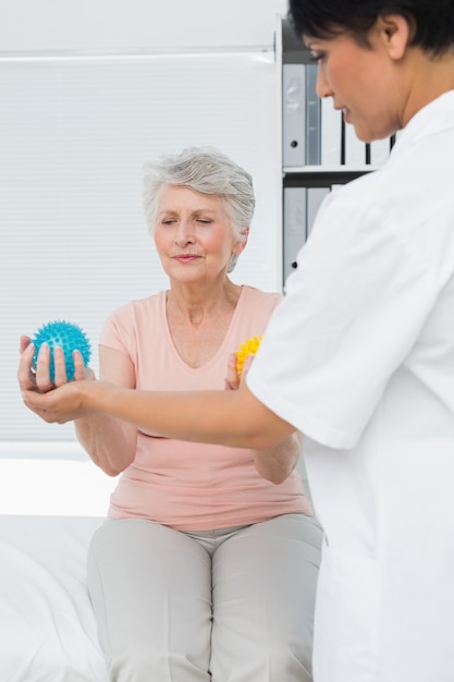 Médico com paciente sênior usando bolas buster stress