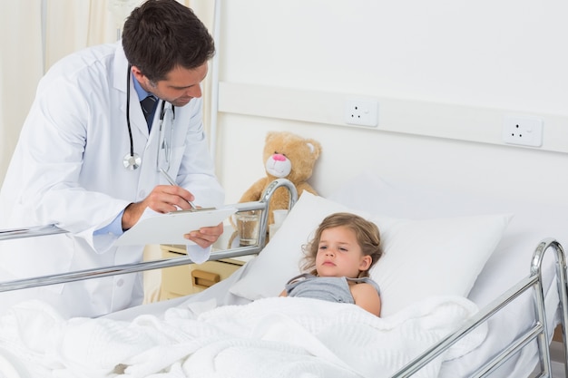 Médico com prancheta atendendo a menina doente