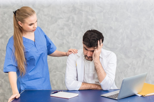 Foto médico com problemas de saúde mental por transtornos psicossomáticos estresse e depressão por sobrecarga de trabalho e enfermeira reconfortante.