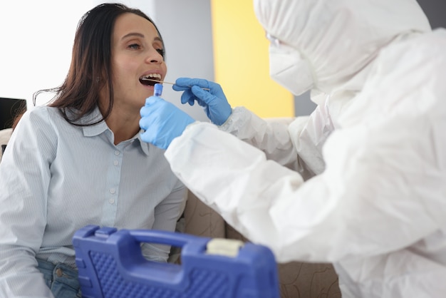 Médico com traje de proteção branco faz o teste de covid19 com a boca