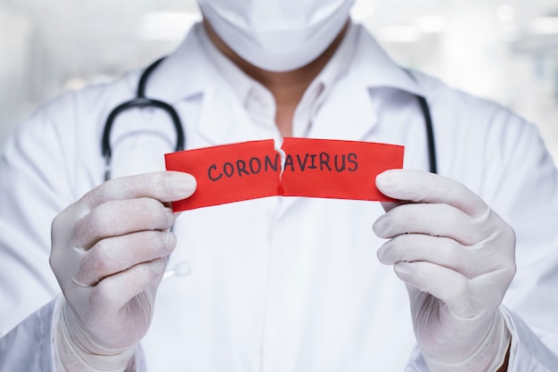 Médico com um estetoscópio Rasgando o papel vermelho com a palavra coronavírus.