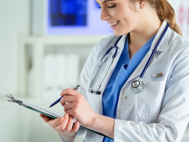 Médico com um estetoscópio segurando um notebook na mão closeup de uma médica preenchendo o médico