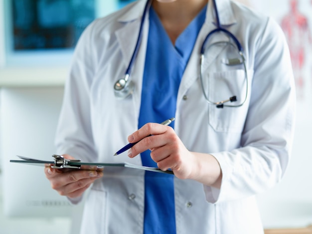 Médico com um estetoscópio segurando um notebook na mão closeup de uma médica preenchendo o médico