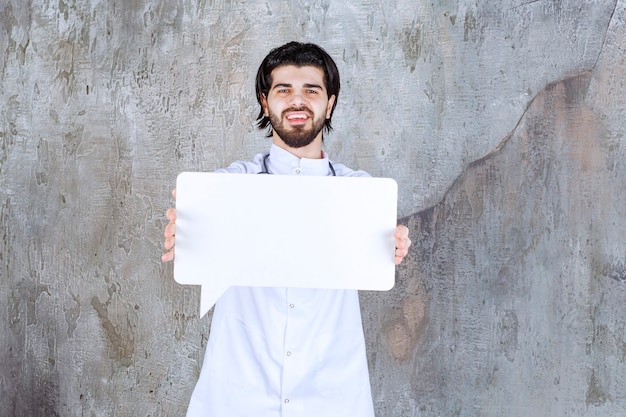 Médico com um estetoscópio segurando um quadro de informações em branco em forma de retângulo