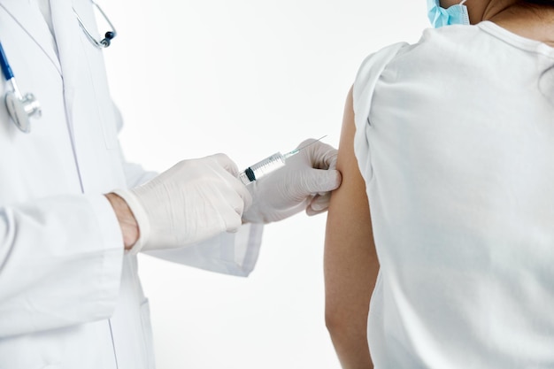 Médico com uma seringa na mão injetando uma vacina em luvas de proteção em um hospital covid