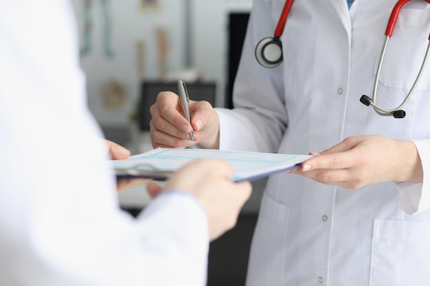 Médico com vestido de médico colocar sinal na prancheta com papel prescrito