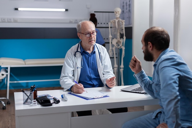 Médico comparecendo à consulta médica com o paciente no gabinete. Médico de clínica geral e pessoa conversando sobre doenças, tratamento de saúde e remédios para recuperação. Exame de saúde