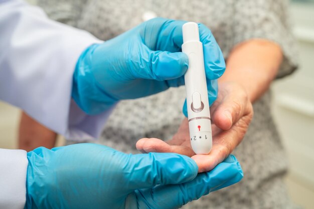 El médico comprueba la diabetes a partir del nivel de azúcar en la sangre del dedo con una lanceta del dedo