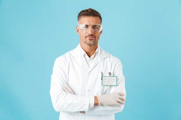Médico confiante usando uniforme e óculos, isolado na parede azul