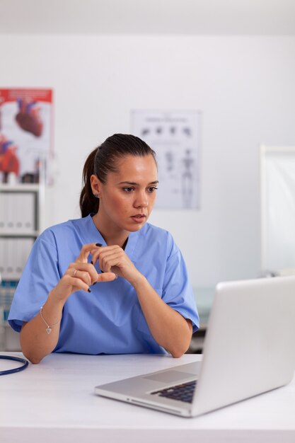 Médico confundido en la oficina del hospital mientras trabaja en la computadora portátil. Médico sentado en el escritorio usando la computadora en la clínica moderna mirando el monitor, medicina.