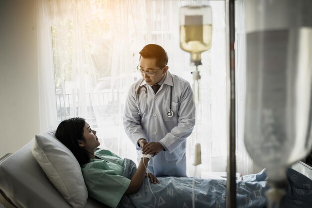 Foto un médico consola a un paciente acostado en una cama en el hospital