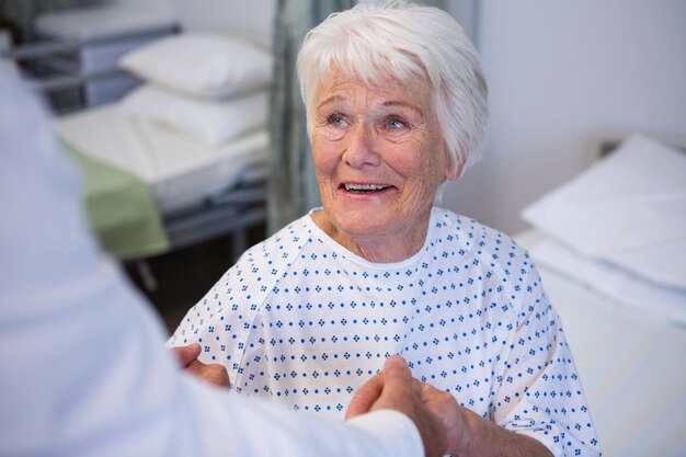 Foto médico consolando paciente sênior na enfermaria