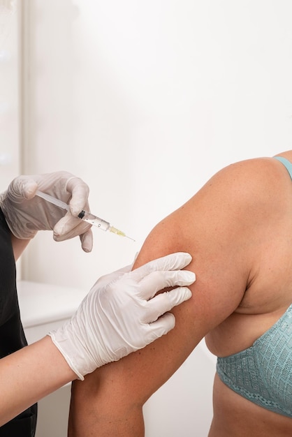 Foto médico cosmetologista faz uma injeção no braço do paciente