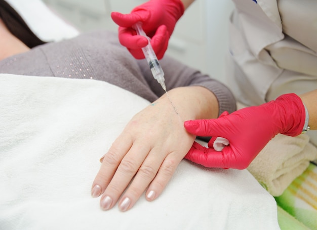 El médico cosmetólogo dermatólogo realiza una sesión de mesoterapia o biorevitalización-eliminación de pigmentación en las manos de las mujeres mayores. Introducción de ácido hialurónico debajo de la piel para rejuvenecimiento.