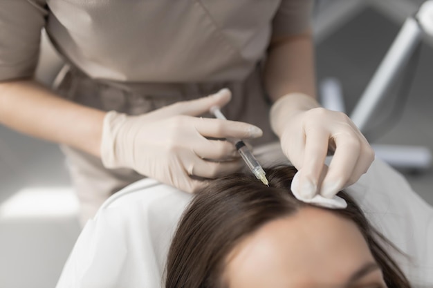 Médico cosmetólogo hace inyecciones de mesoterapia para el cabello a un cliente Restauración y cuidado del cabello