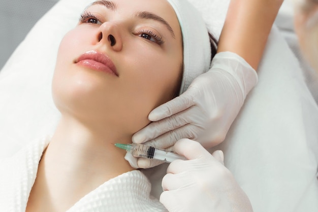 El médico cosmetólogo realiza el procedimiento de inyecciones faciales rejuvenecedoras para tensar y
