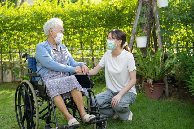 Foto médico cuidador ayuda y cuidado mujer anciana asiática paciente sentada en silla de ruedas en el parque