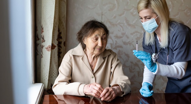 El médico le da una inyección a la anciana.