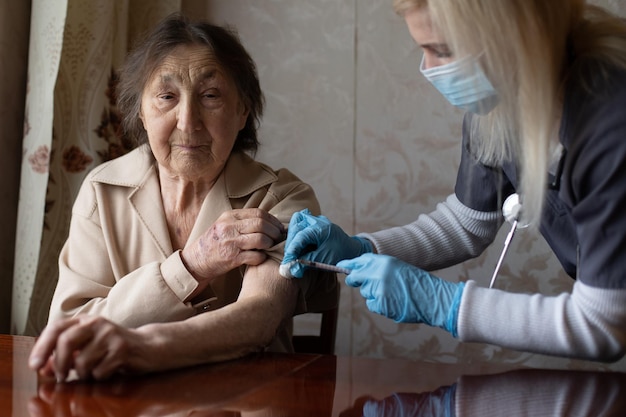 El médico le da una inyección a la anciana.