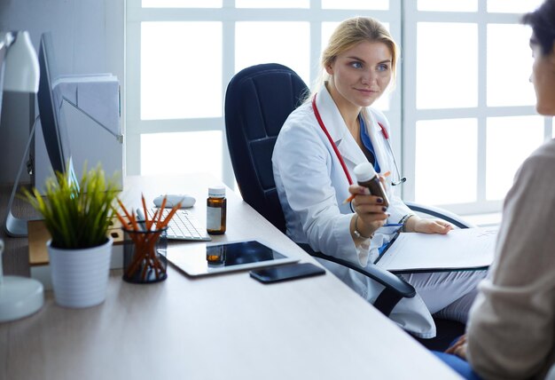 Médico da mulher mostrando um frasco de comprimidos para o paciente